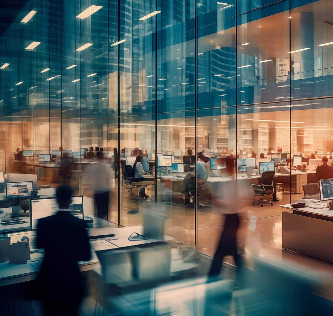 Office building with a large room full of tables and people working and part of the staff walking between the tables.