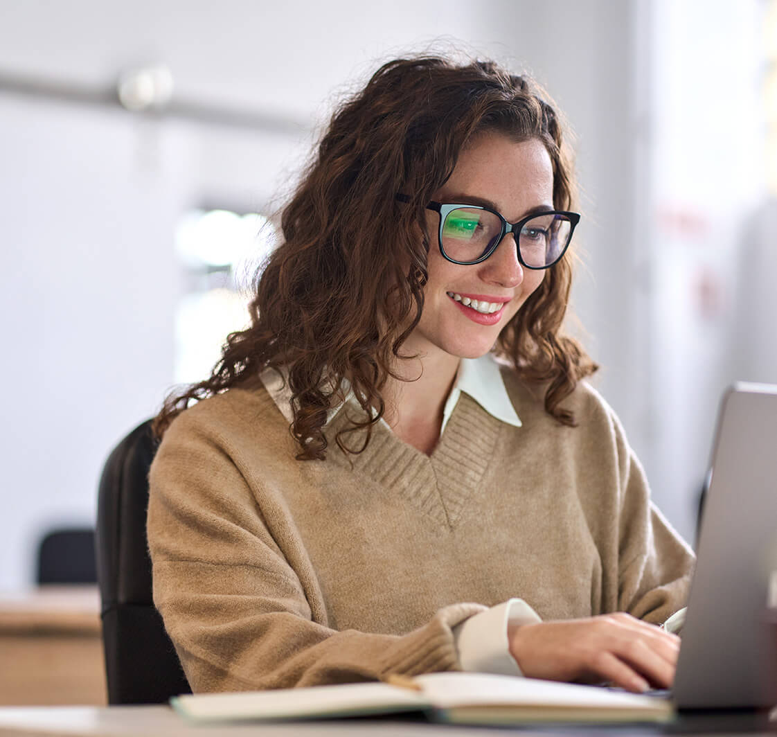 Smiling female student using computer technology learning online, doing web research.