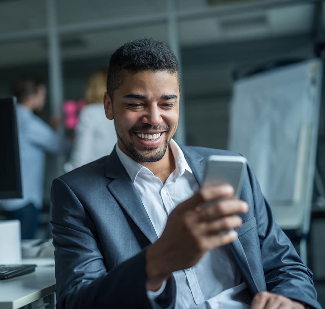 Business man looking at his mobile phone and smiling.