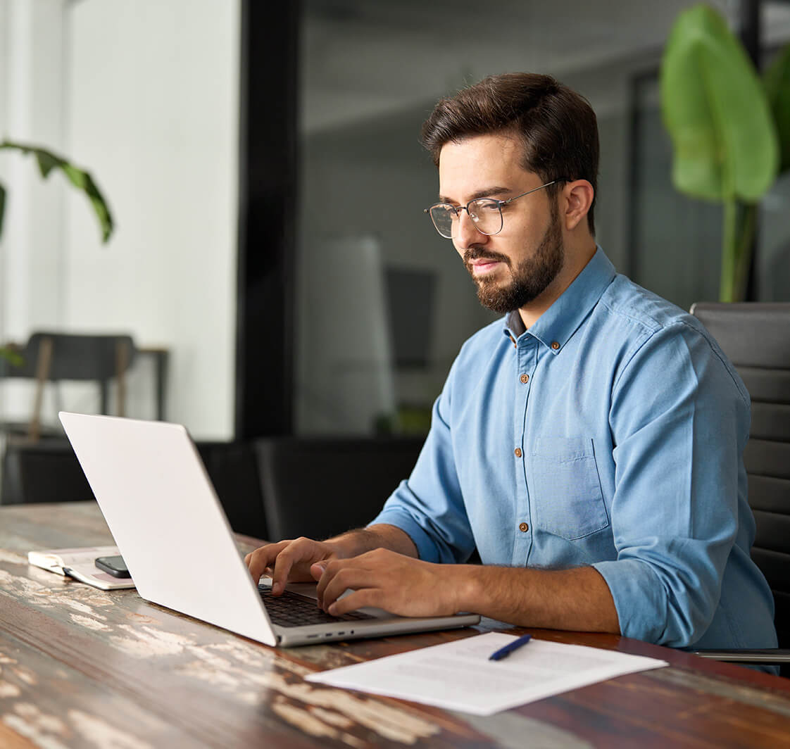 Businessman wearing glasses typing on computer technology using laptop searching on web working at office workplace desk.