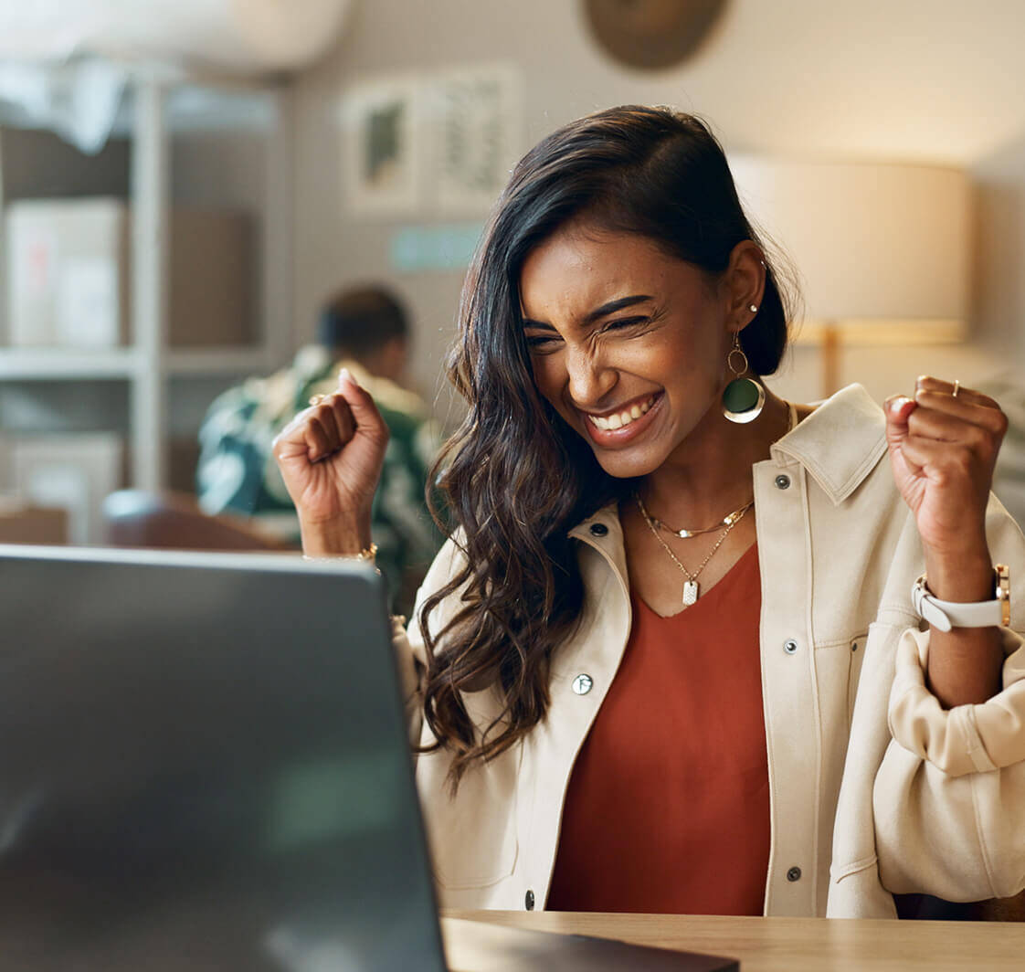 Business woman celebrating while looking at a computer screen.