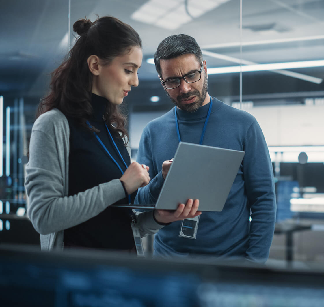 Portrait of Two Female and Male Engineers Using Laptop Computer to Analyze and Discuss data.