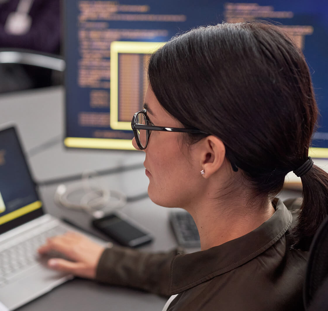 Side view portrait of woman as female IT engineer working with data at desk.