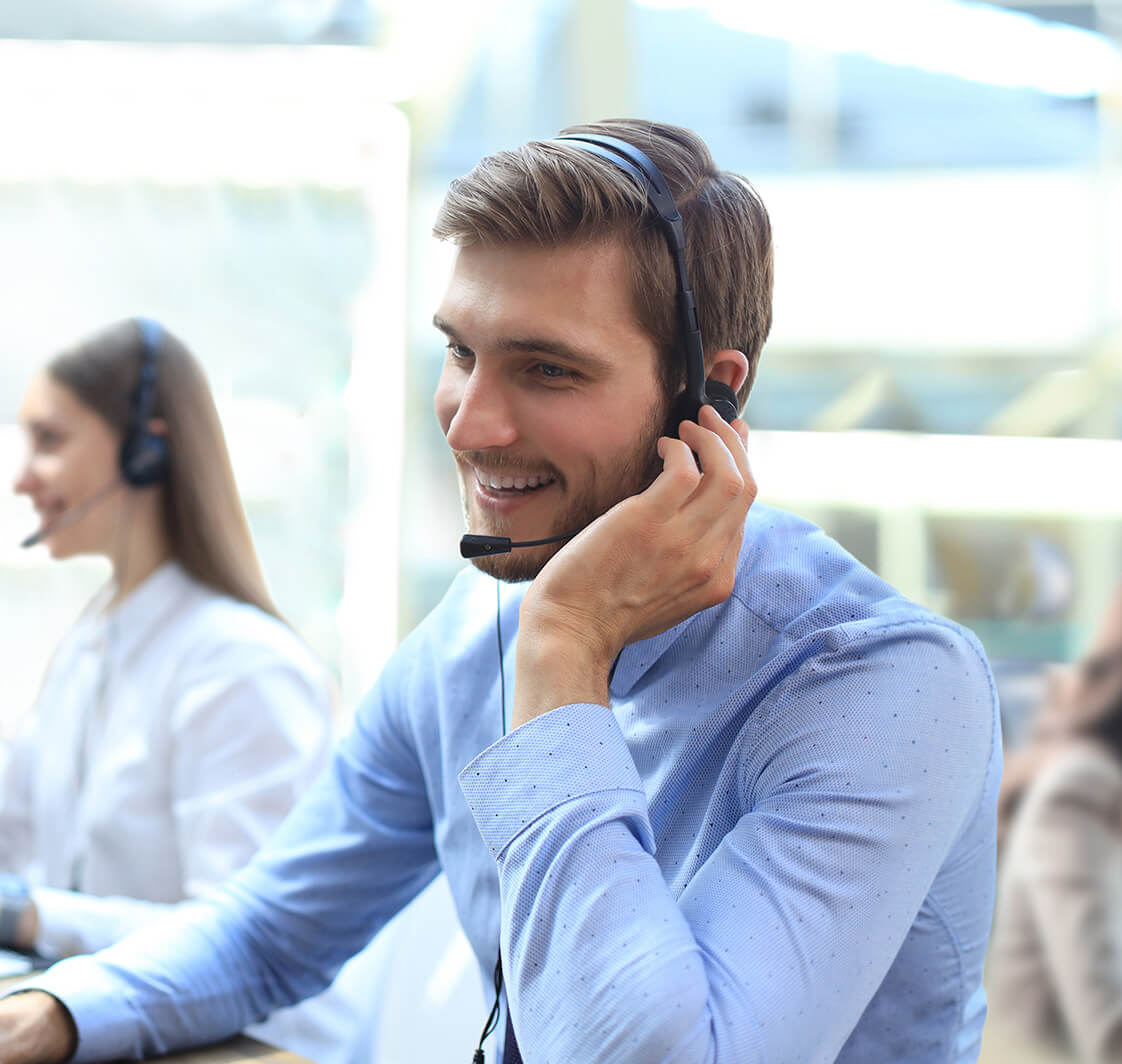 Portrait of call centre worker accompanied by his team. Smiling customer support operator at work.