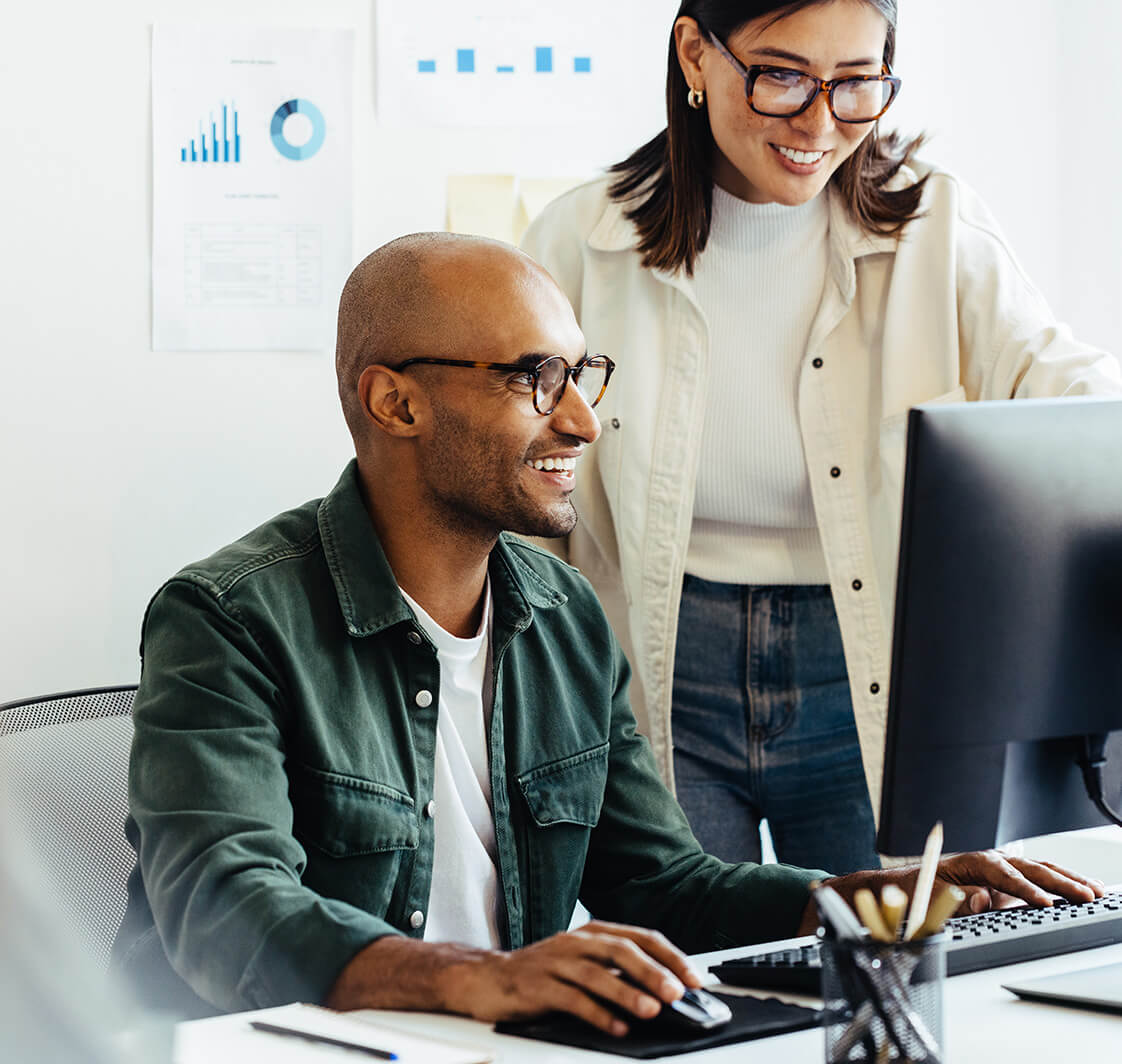 Web developers using a computer together in an office.