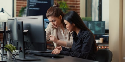 Software developers collaborating on data coding group project while sitting at desk.