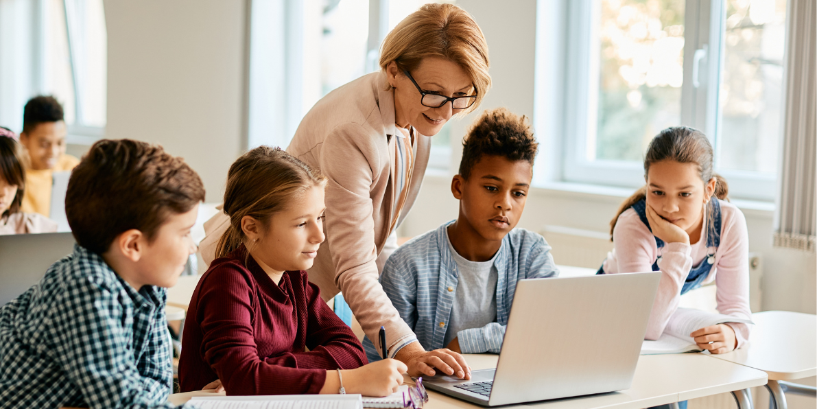 School teacher and young students working on a laptop